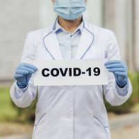 close-up-doctor-holding-covid-sign